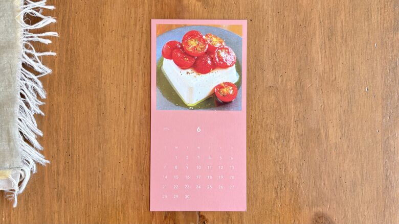 木のテーブルに置かれた、料理写真付きの月刊レターのカレンダー