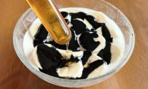 黒ねりごまをかけたヨーグルトにはちみつを加えるところ