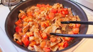豚バラ肉とトマトに醤油を加えて炒め合わせた様子