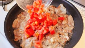 豚バラ肉を焼いたフライパンにトマトを加えた様子