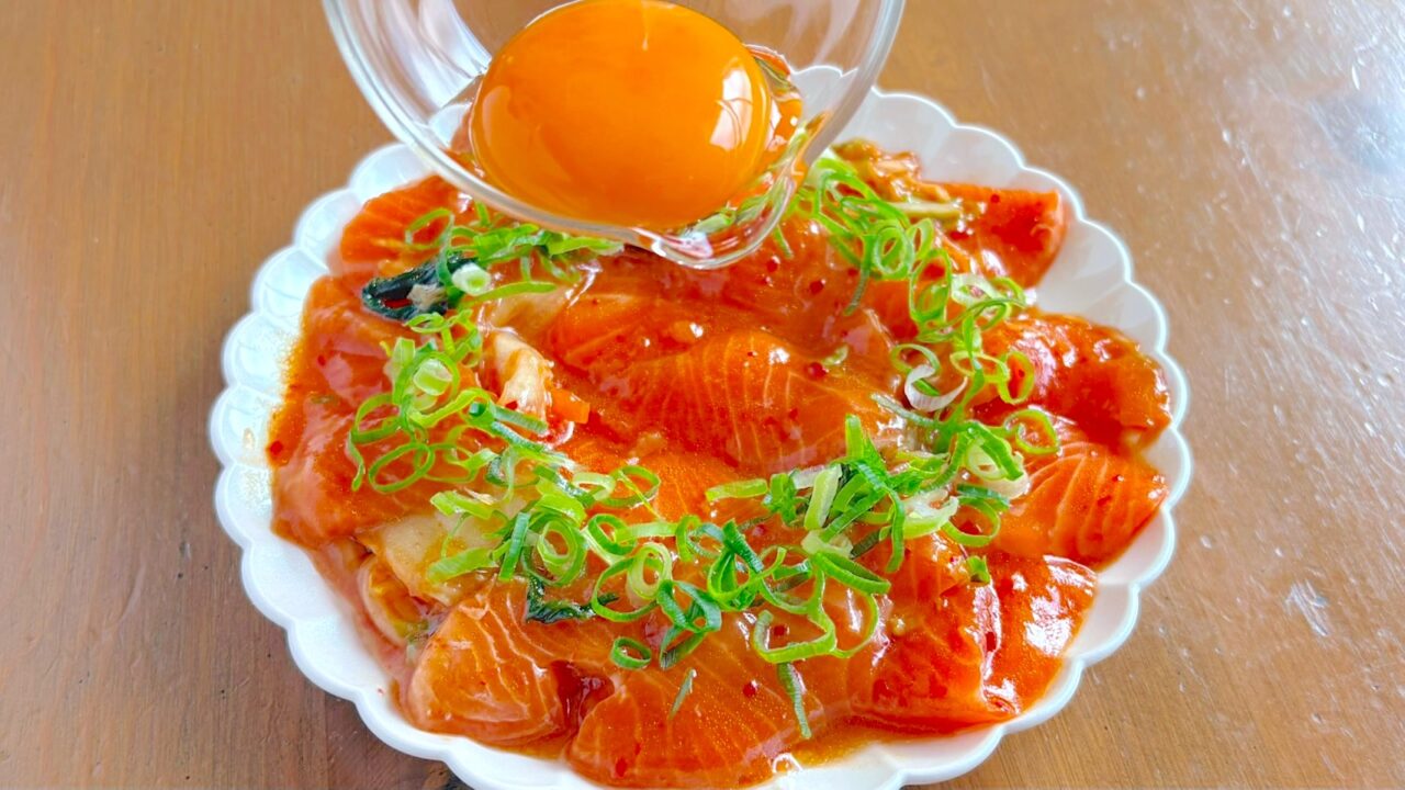 盛り付けたサーモンとキムチに卵黄をのせるところ