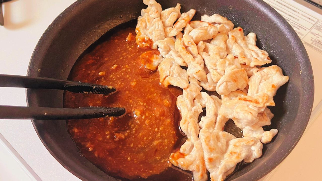 フライパンの空いた場所で中濃ソース、味噌、水を混ぜる様子
