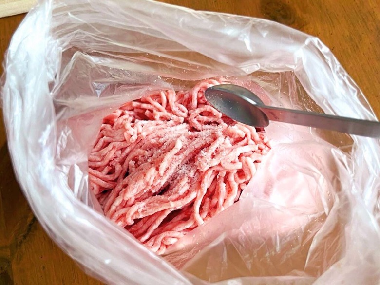 ポリ袋に入れた豚ひき肉へ塩を加える