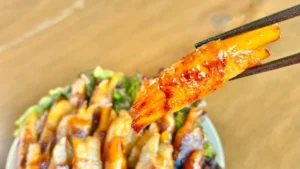 箸で持ち上げたじゃがいもの豚バラ巻き照り焼き