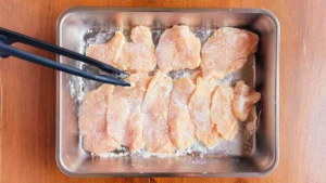 斜め薄切りにした鶏むね肉へ塩を振る様子