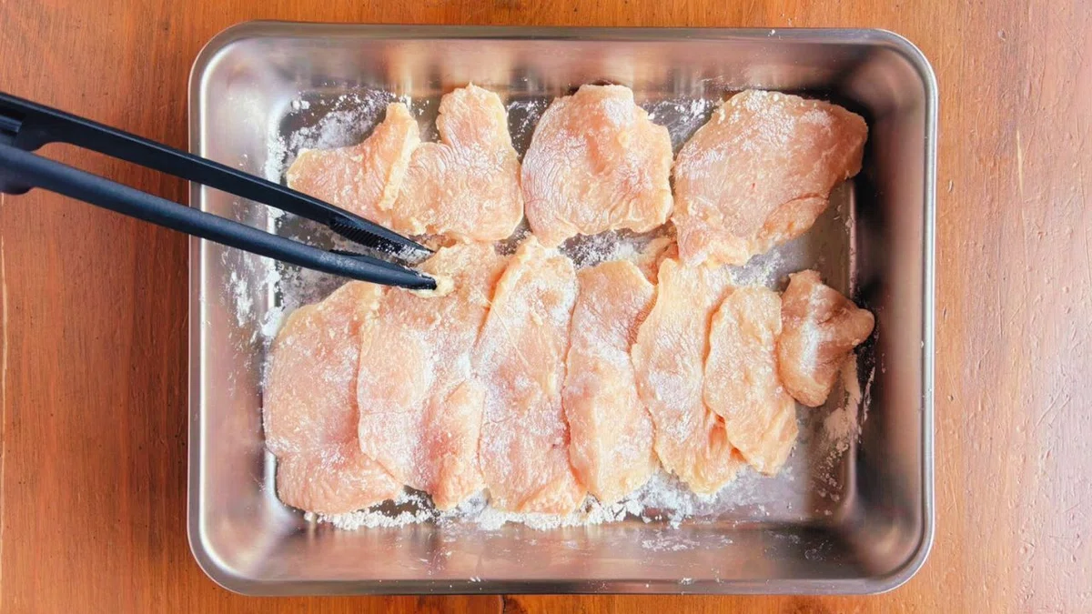 斜め薄切りにした鶏むね肉へ塩を振る様子