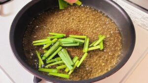 沸騰したスープにニラを加える様子