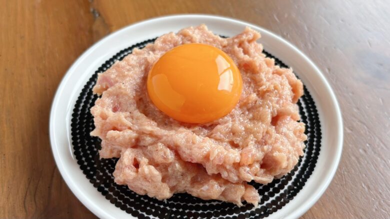 器に盛ったマグロのたたきへ卵黄をのせた様子