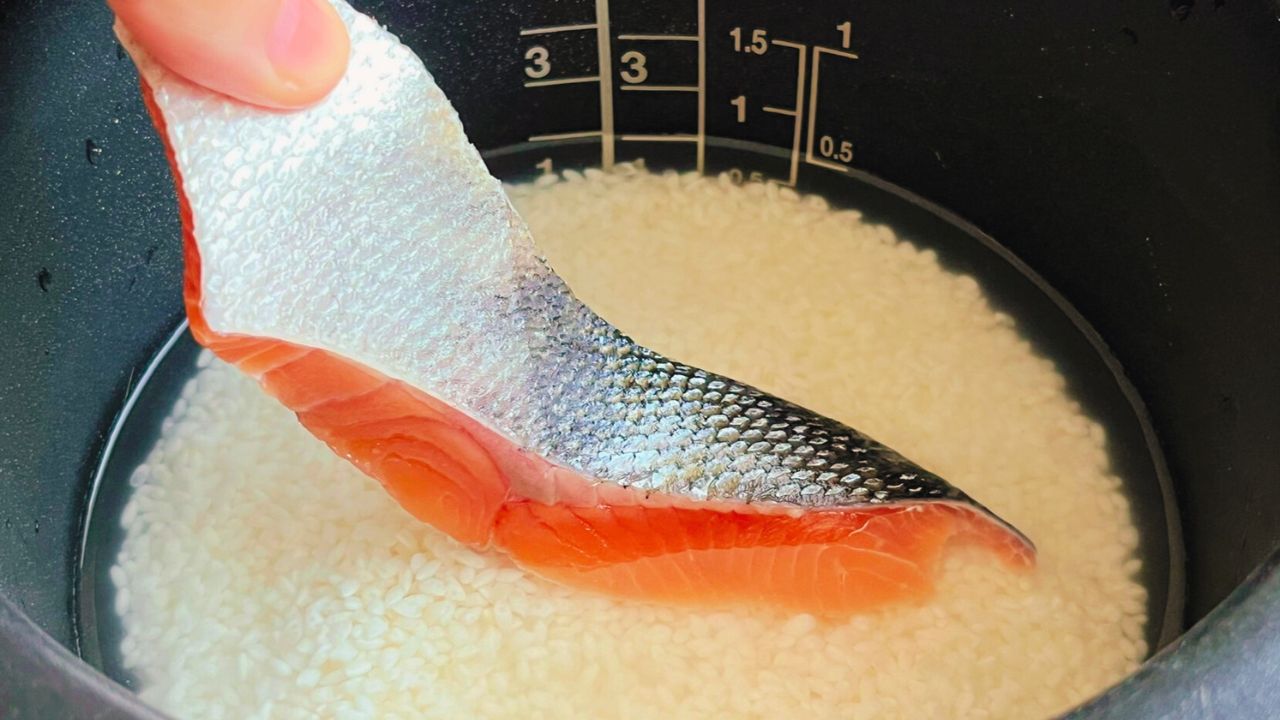 炊飯釜の米に鮭をのせるところ