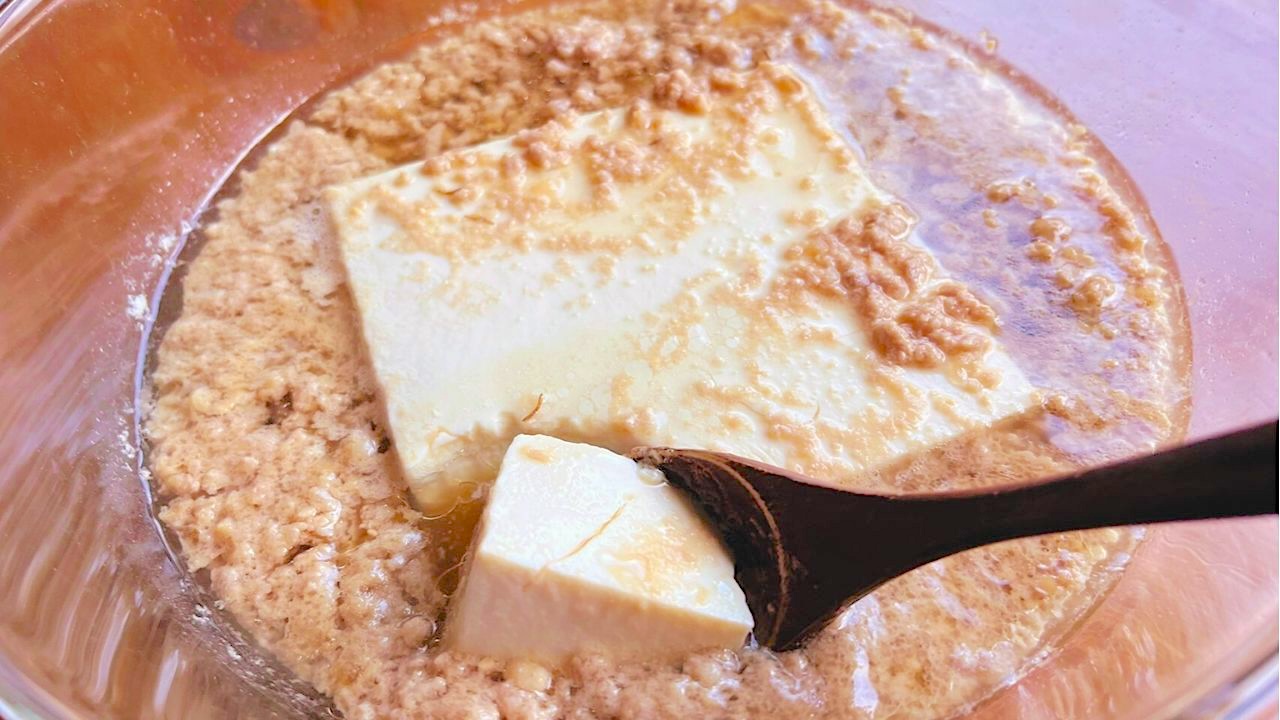 加熱した豆腐を木のスプーンで崩しながら混ぜる
