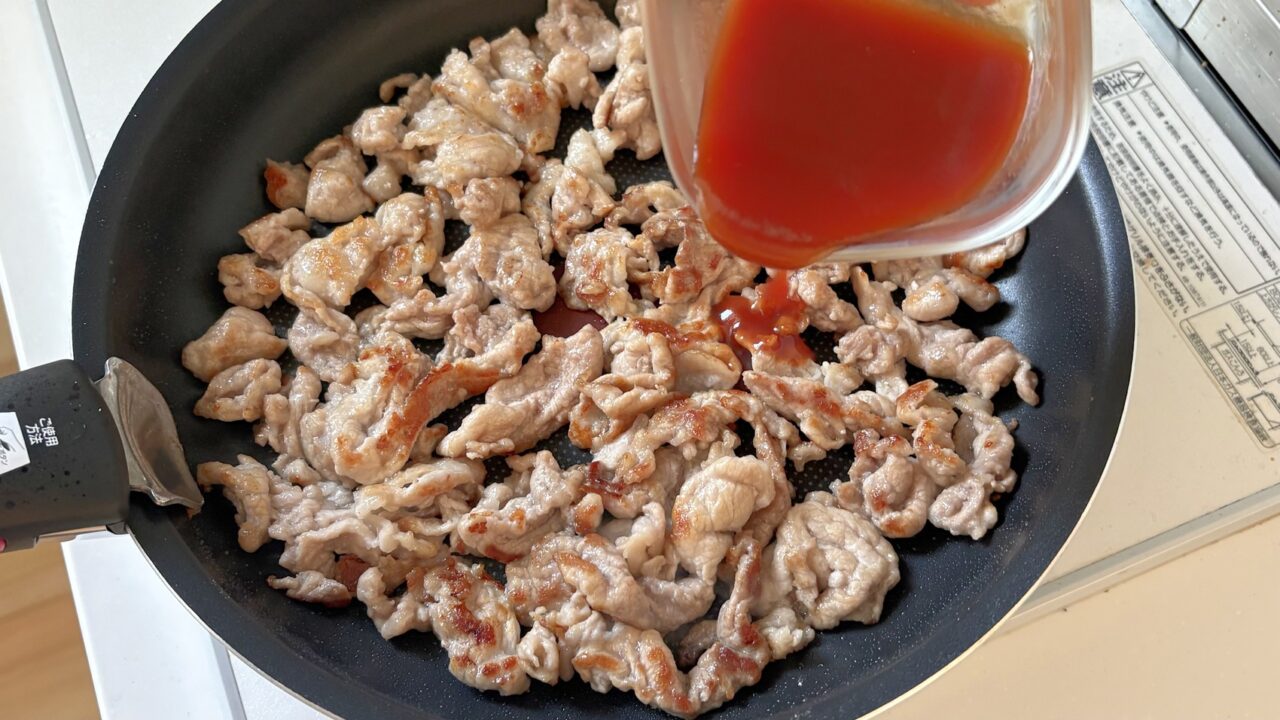 焼いた豚こま切れ肉にケチャポンだれを加えるところ