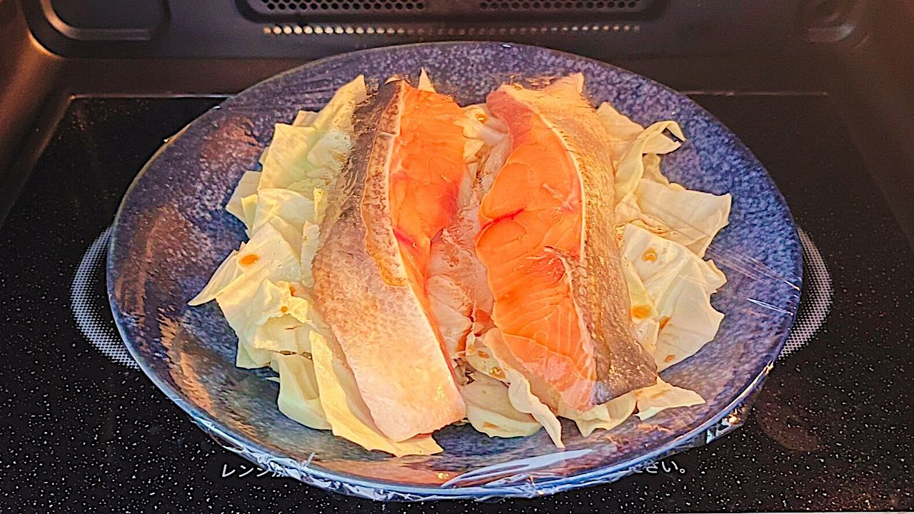 ラップをかけた鮭とキャベツを電子レンジで加熱するところ