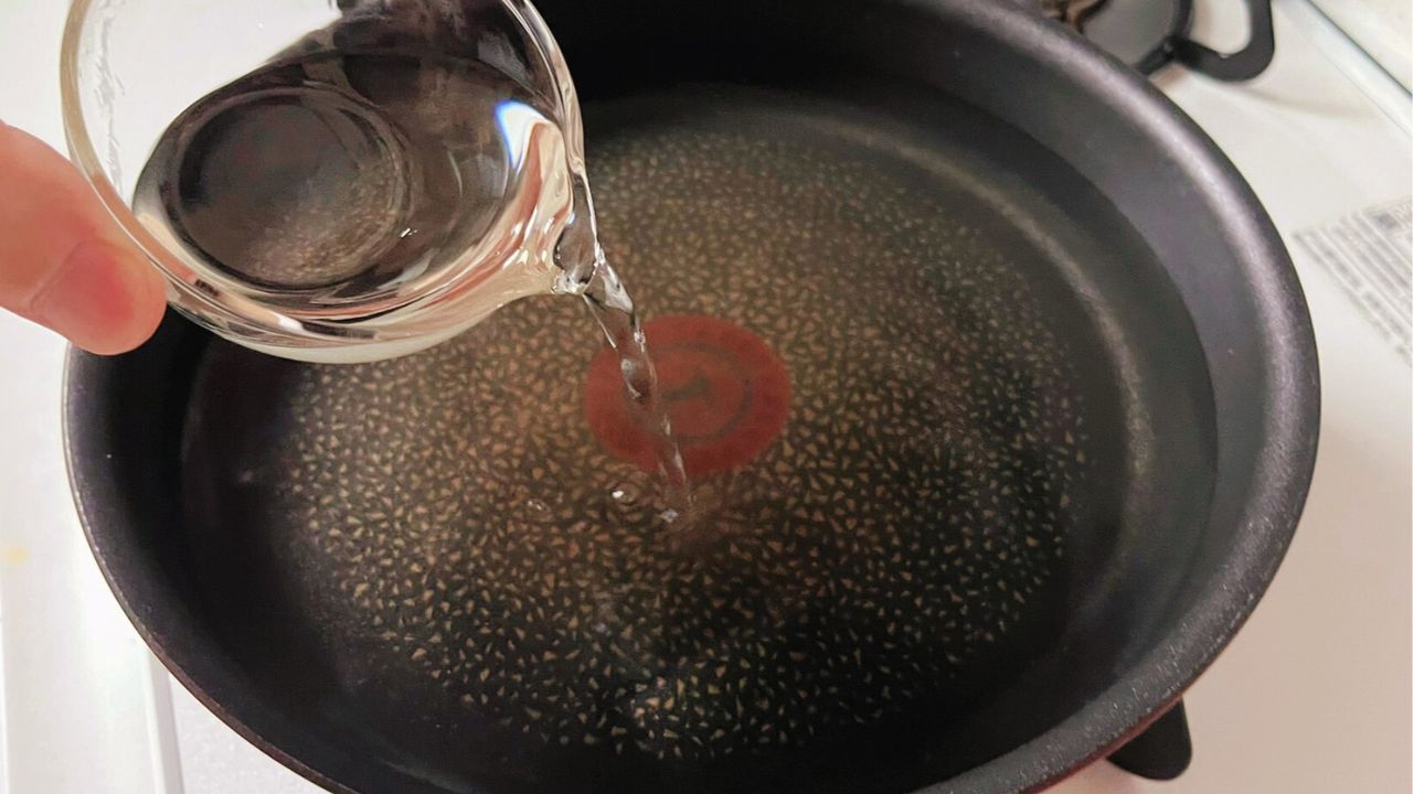 フライパンに酒を加えるところ