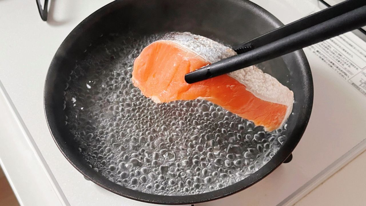 沸騰した湯に塩鮭を入れるところ